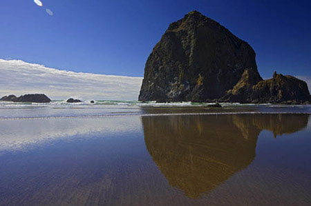 Haystack Rock is reflected in the waters of Cannon Beach